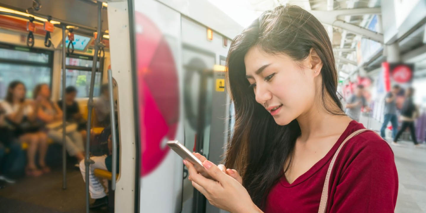 A woman uses a smartphone at a train platform