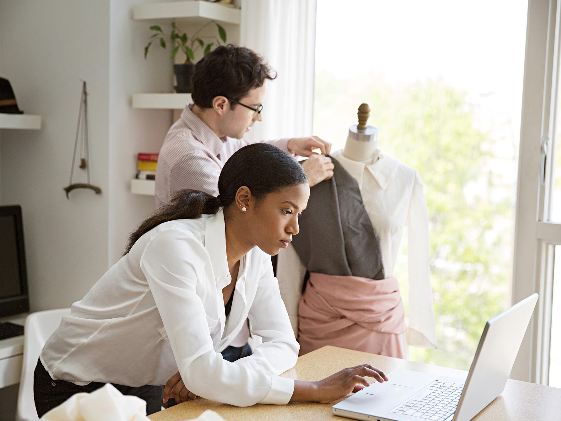 A black woman clothing business owner looks at a laptop