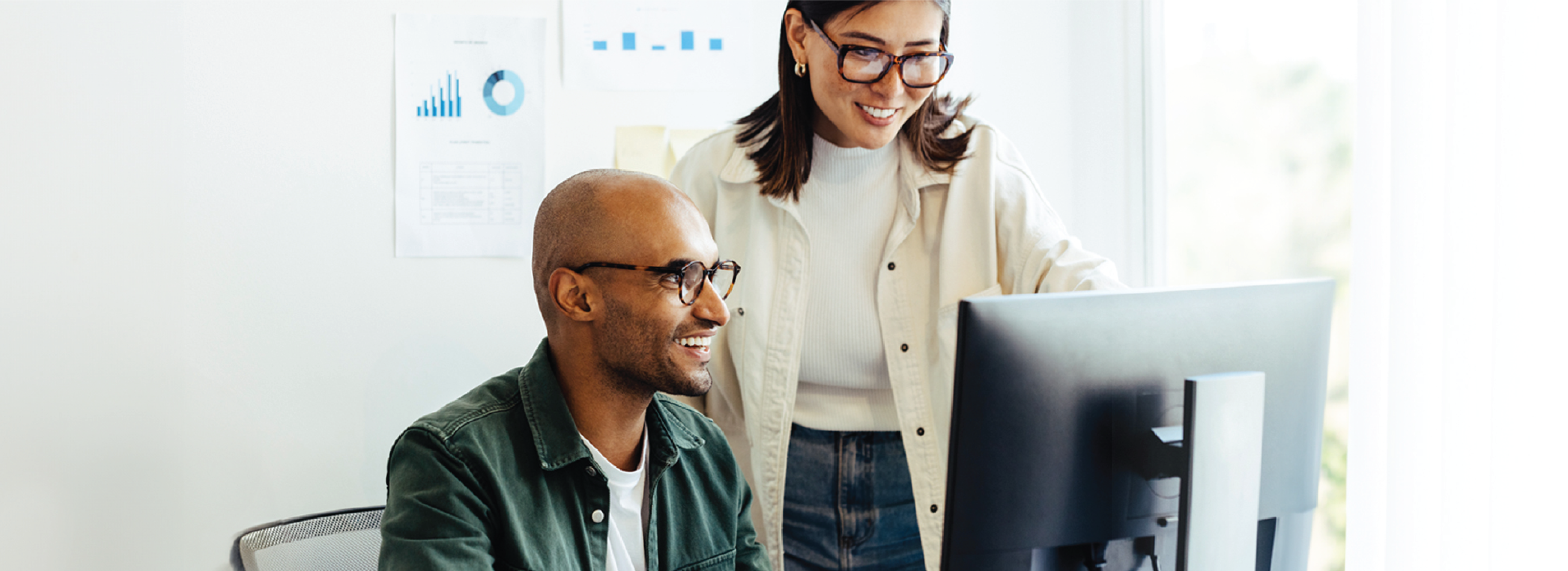 Blog cover image showing two people talking at a desk in front of a computer 