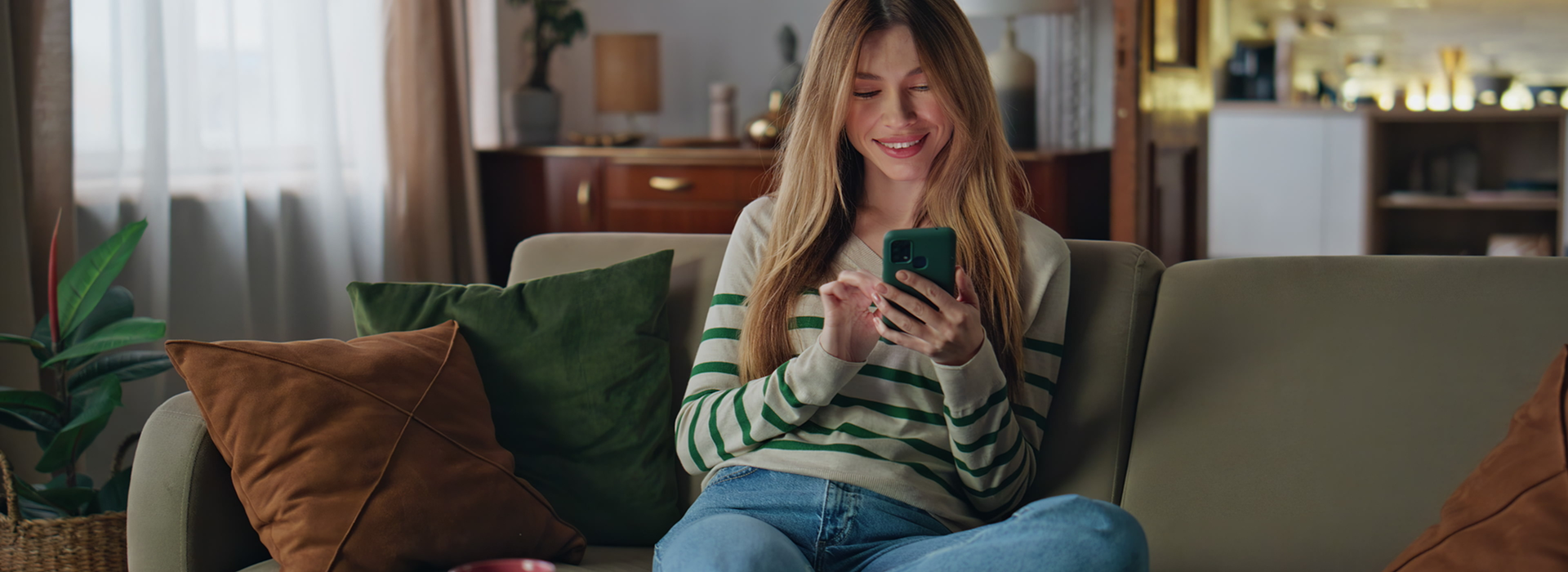 Woman casually browsing on phone while seated in a living space