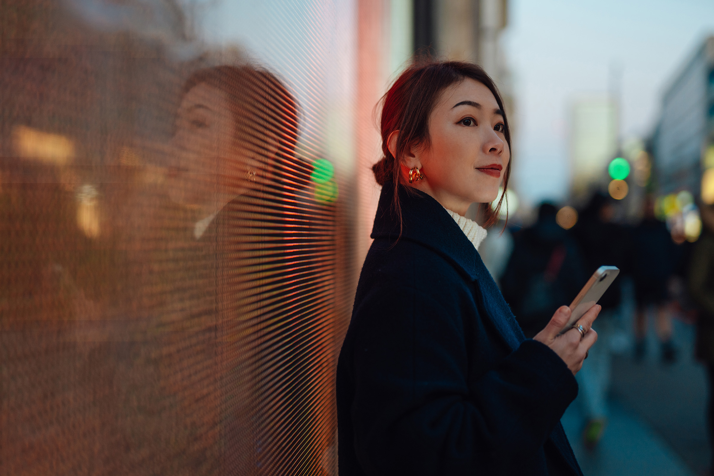 Woman holding phone against orange wall